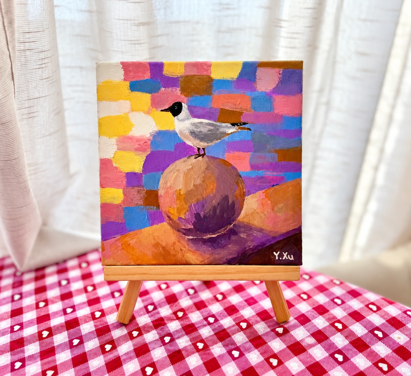 A colourful painting of a black-headed gull displayed on a small wooden easel